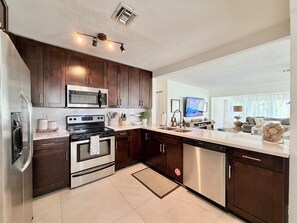 A modern kitchen with dark wood cabinets, stainless steel appliances, and a large island with a sink.