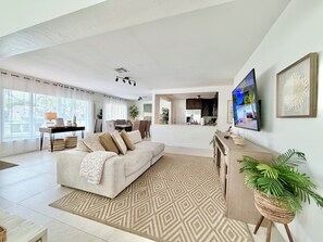 Ein geräumiger Wohnbereich mit Sofa, Esstisch und einer Küche im Hintergrund.