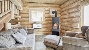 A log cabin interior with a fireplace, wooden walls, a sofa, and a television. - Yellowstone by Summit Lodges (Pfunds)