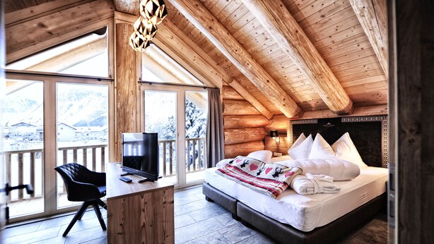 A log cabin bedroom with a bed, a desk, and a chair. - Yellowstone by Summit Lodges (Pfunds)