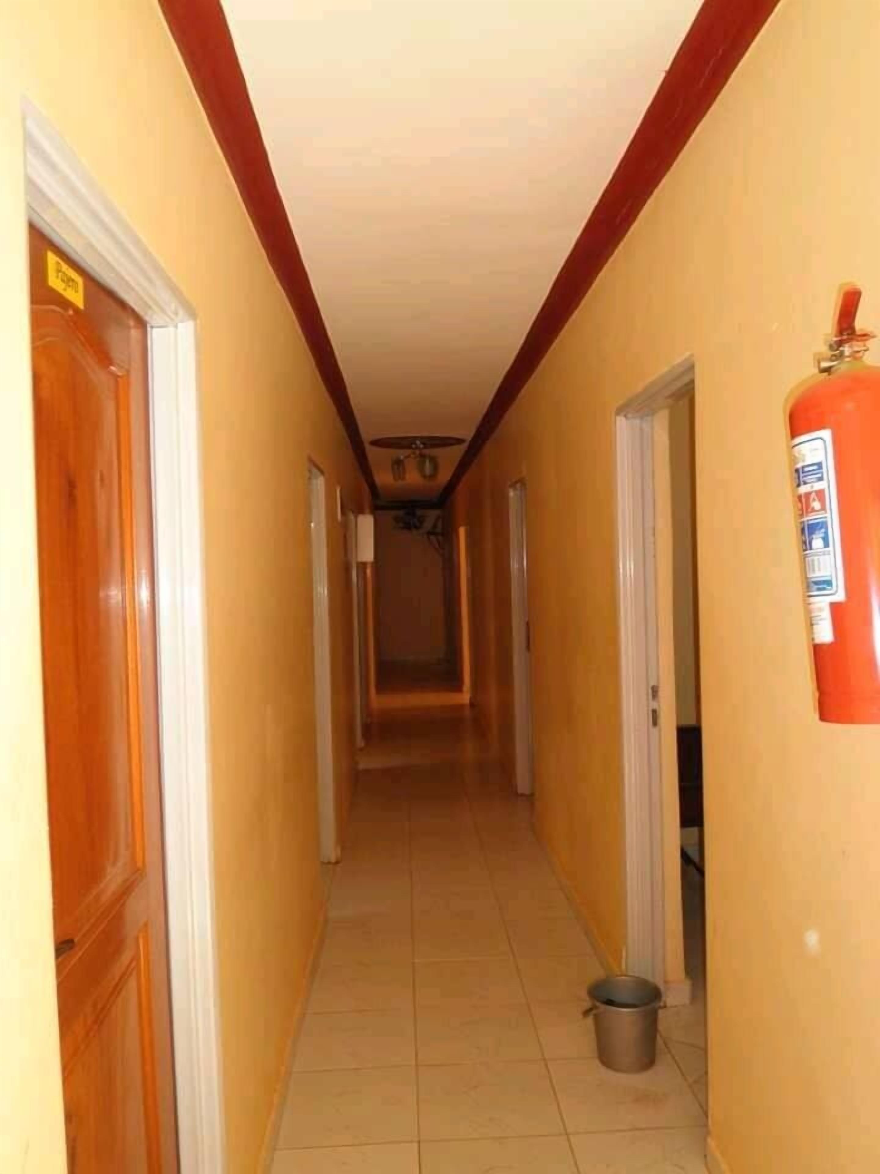 Un pasillo estrecho con puertas de madera y un extintor en la pared.