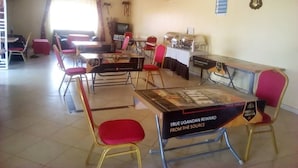 Un espace repas avec des tables et des chaises, une horloge et un tableau encadré au mur.