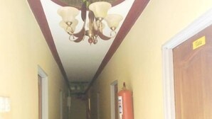 Un couloir étroit, orné d’un lustre, muni d’un extincteur et dont la porte porte l’inscription « Tuta ».