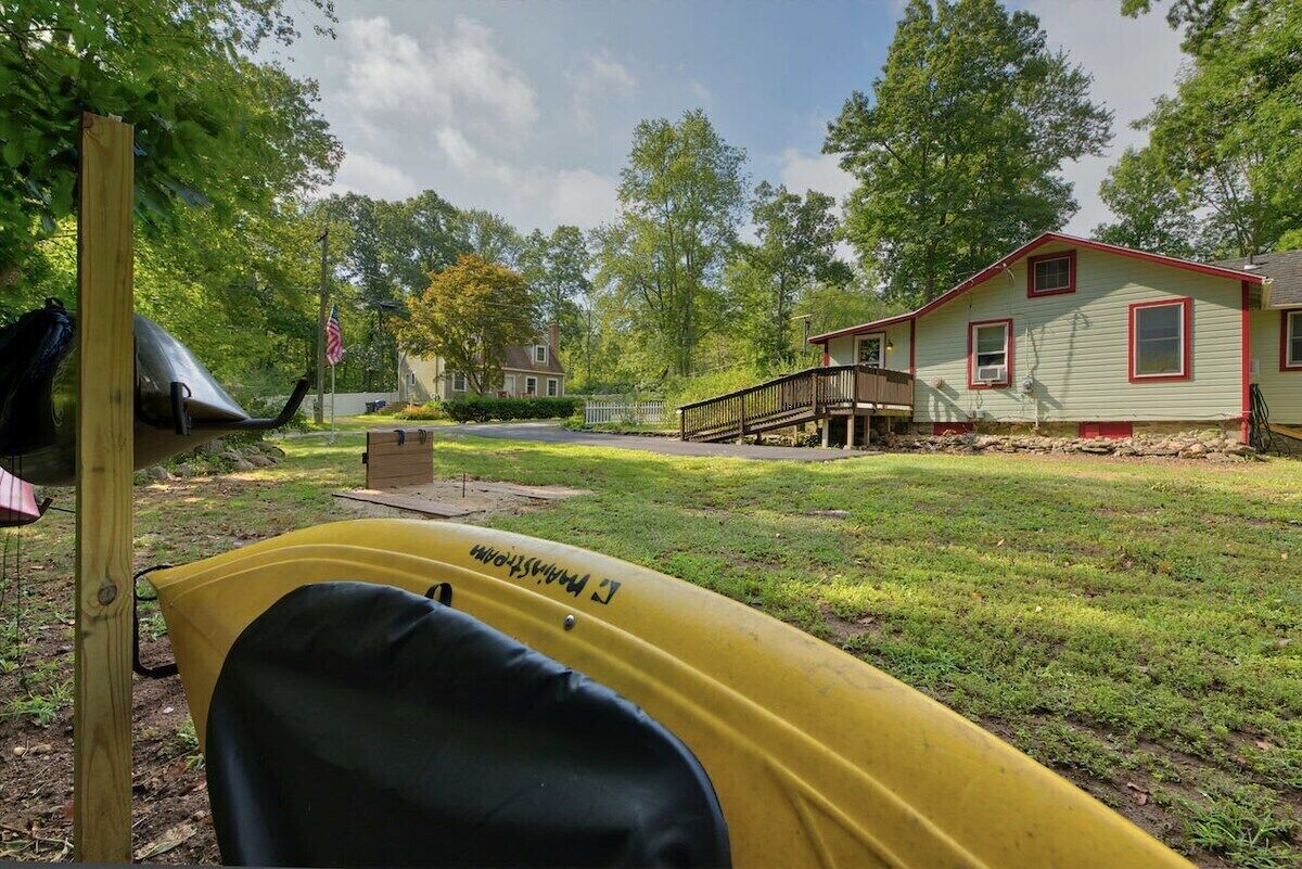 A yellow kayak in a backyard with a house and trees in the background.