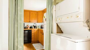 A compact kitchen with wooden cabinets, a dishwasher, and a white appliance, possibly a washer or dryer.
