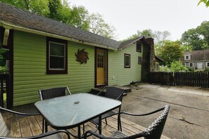 Ein grünes Haus mit einer Terrasse, einem Tisch und Stühlen.