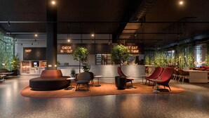 A modern interior with seating areas, a counter with a neon sign, and indoor plants. - Scandic Örebro Central (Örebro)