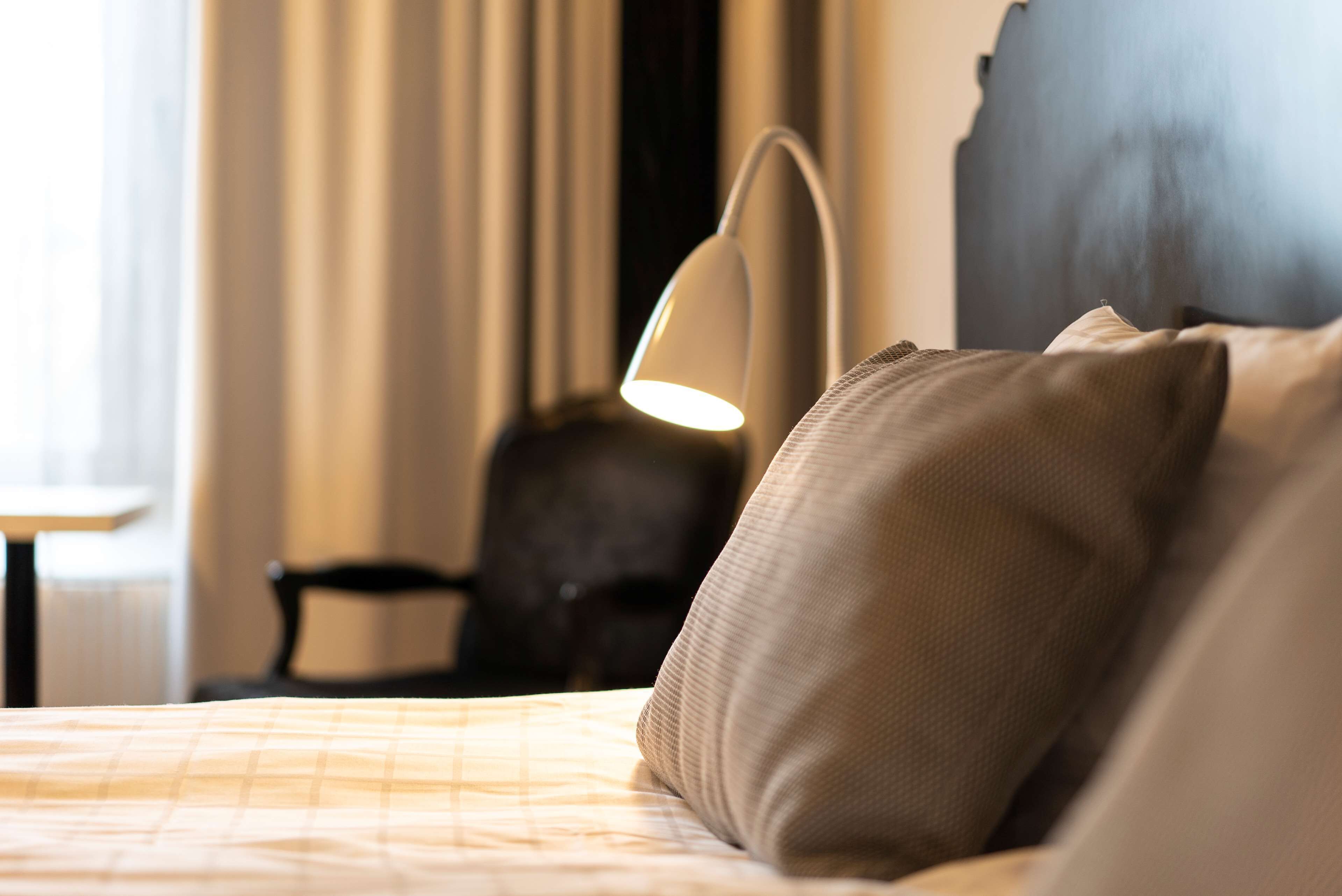 A hotel room with a bed, a lamp, and a chair.