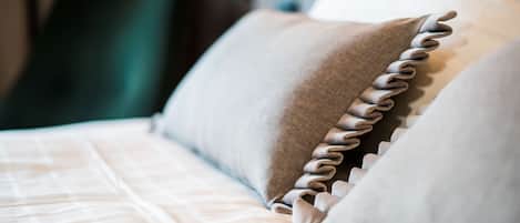 A close-up of a bed with a neatly arranged pillow and a pillow with a ruffled edge.