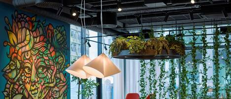 A modern conference room with a colorful mural, round tables, and red chairs.