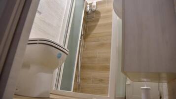Ein Badezimmer mit Toilette, einer Duschkabine und einem Waschbecken.