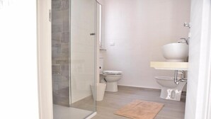 A bathroom with a glass shower enclosure, two toilets, a sink, and a woven mat on the floor. - Double room in the center of Catania (Catania)