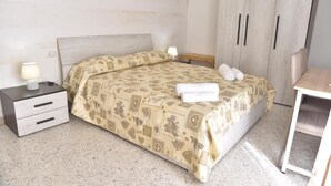 A bedroom with a bed, nightstands, a wardrobe, and a small table. - Double room in the center of Catania (Catania)