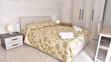 Ein Schlafzimmer mit einem Bett, Nachttischen, einem Kleiderschrank und einem kleinen Tisch.
