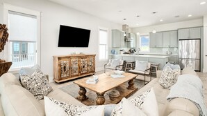 A modern living room with a sofa, coffee table, and a TV mounted on the wall. - Gulf-Front Pool | Foosball | Elevator (Miramar Beach)