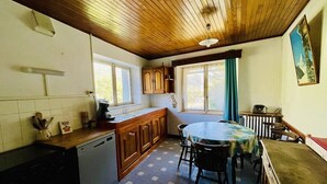 Una cocina con techo de madera, una mesa de comedor y un ventanal con cortinas.