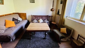 Una habitación acogedora con techo de madera, un sofá con cojines, una mesita y una ventana con cortinas.