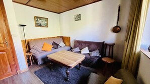 Una sala de estar acogedora con techo de madera, un conjunto de sofás, una mesa de centro y una lámpara.