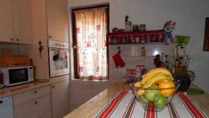A kitchen with a microwave, a bowl of fruit on the counter, and a red oven mitt hanging on the wall. - Impeccable Apartment With View in Dolna Matka (Matka)