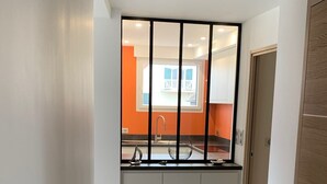 A narrow hallway leading to a kitchen with a window, white cabinets, and a tiled floor. - LE CLOS DES 2 CAPS - RENOVATED CONTEMPORARY 2 BED APARTMENT 2 STEPS FROM THE SEA (Wimereux)