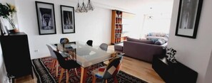 Ein modernes Wohnzimmer mit einem Glastisch, schwarzen Stühlen, einer Couch und einem Bücherregal.