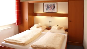 A double bed with two pillows and a bedside table with a lamp. - Apartments Zur alten Post (Willingen)