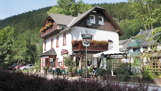 A traditional building with a balcony, outdoor seating, and a sign indicating it is a restaurant. - Apartments Zur alten Post (Willingen)