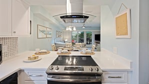Een moderne keuken met een centraal eiland, roestvrijstalen apparatuur en een eetgedeelte met uitzicht.