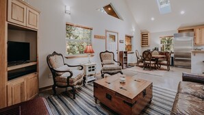 A spacious living room with a high ceiling, wooden cabinets, a television, two armchairs, a coffee table, and a dining area with a table and chairs. - 61mbr - Hot Tub - Wi-fi - Pets Ok - Sleeps 6 3 Bedroom Home by Redawning (Deming)