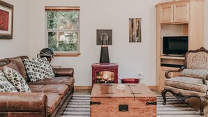 A cozy living room with a leather sofa, a wooden coffee table, a fireplace, a television, and a patterned armchair. - 61mbr - Hot Tub - Wi-fi - Pets Ok - Sleeps 6 3 Bedroom Home by Redawning (Deming)