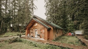 A log cabin with a porch, a hot tub, and a wooden deck. - 61mbr - Hot Tub - Wi-fi - Pets Ok - Sleeps 6 3 Bedroom Home by Redawning (Deming)