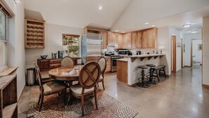 A spacious kitchen with wooden cabinets, a central island with stools, a dining table with chairs, and a large window providing natural light. - 61mbr - Hot Tub - Wi-fi - Pets Ok - Sleeps 6 3 Bedroom Home by Redawning (Deming)