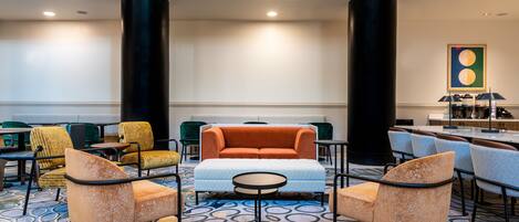 A lobby with a sofa, chairs, a coffee table, and a patterned carpet.