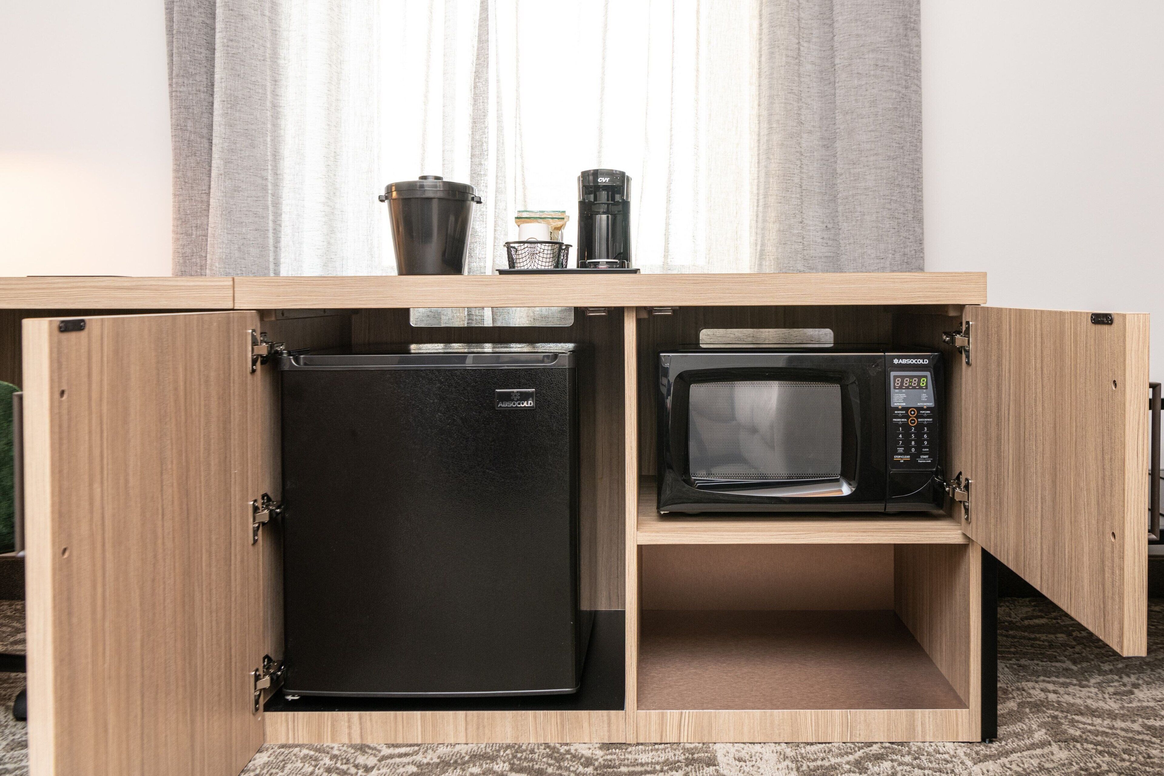 Una cocina con refrigerador y microondas integrados, cafetera y basurero.