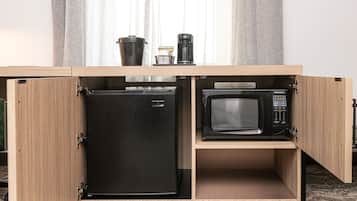 Una cocina con refrigerador y microondas integrados, cafetera y basurero.