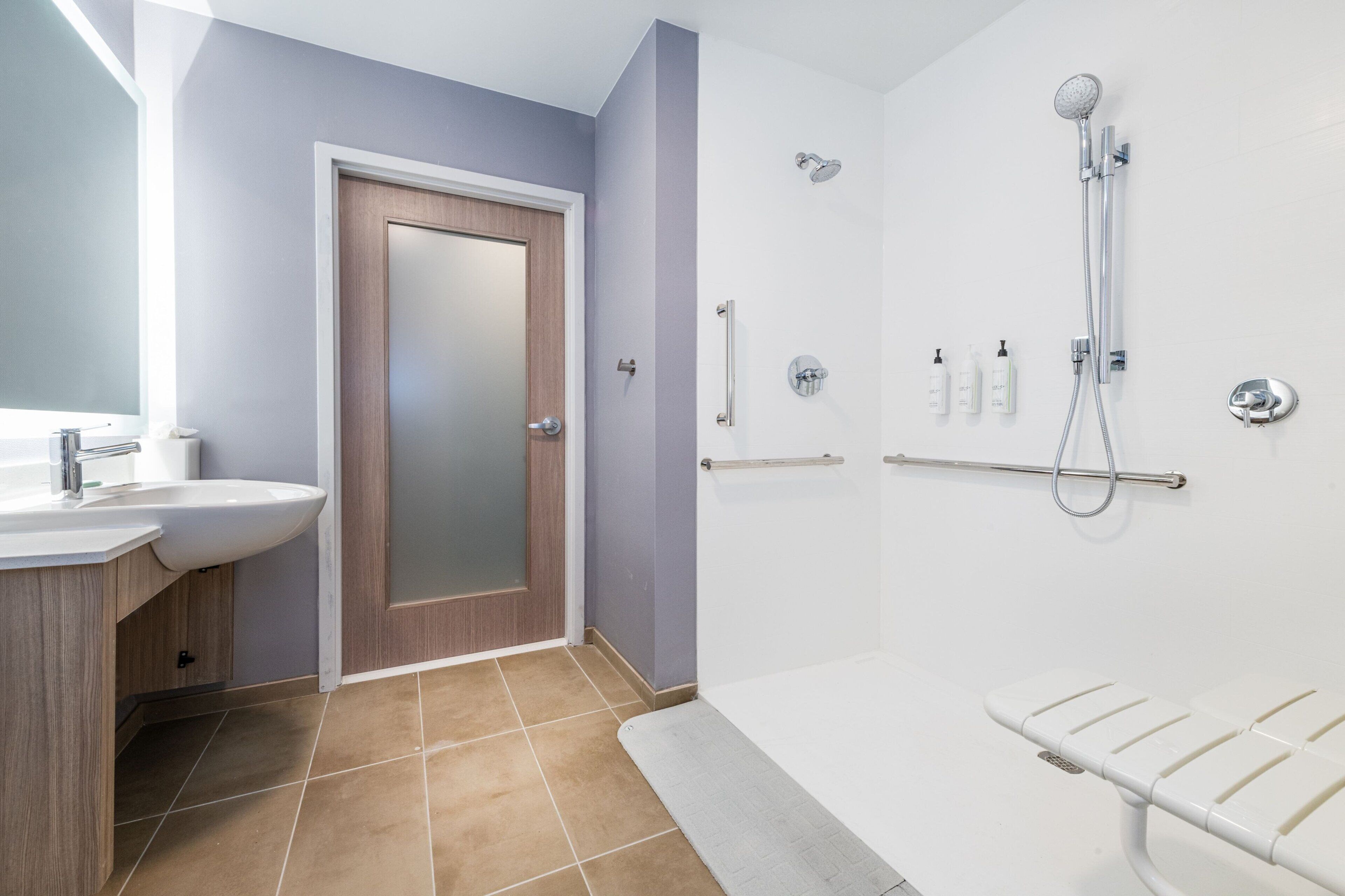 A modern bathroom with a sink, mirror, shower, and towel rack.