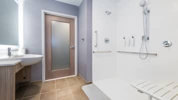 A modern bathroom with a sink, mirror, shower, and towel rack.