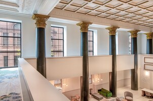 Un amplio vestíbulo con techos altos, ventanas grandes y columnas de estilo clásico.