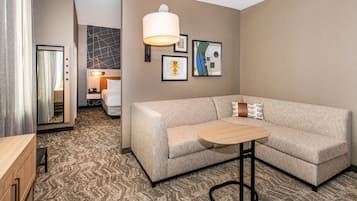 Ein modernes Hotelzimmer mit einer Couch, einem kleinen runden Tisch und einer großen Wandleuchte.