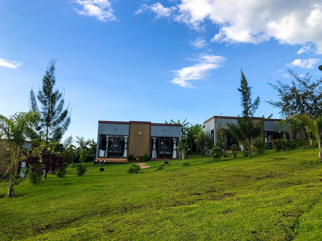 A modern two-story house with a flat roof, large windows, and a well-maintained lawn.