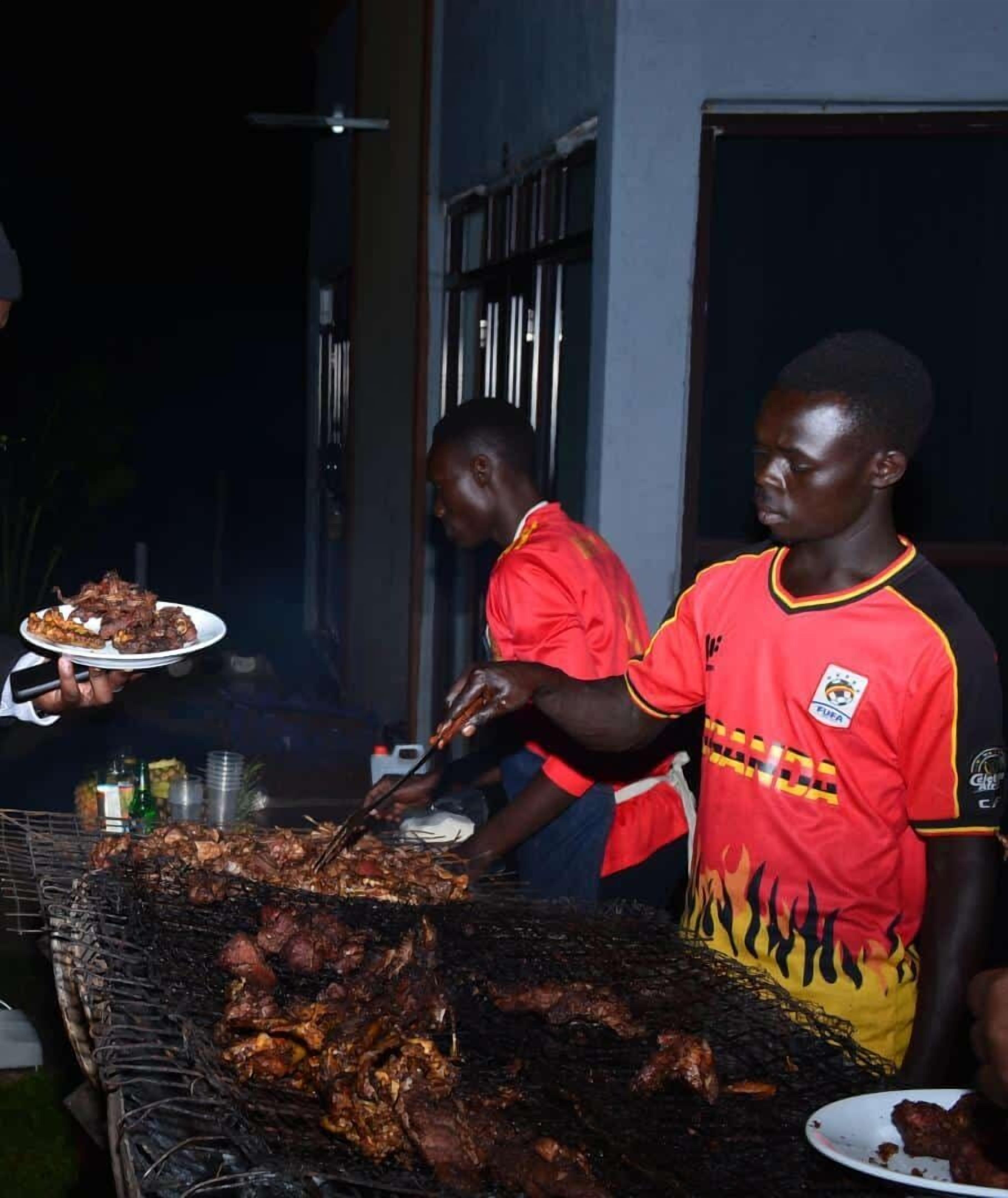 A person grilling meat outdoors at night.