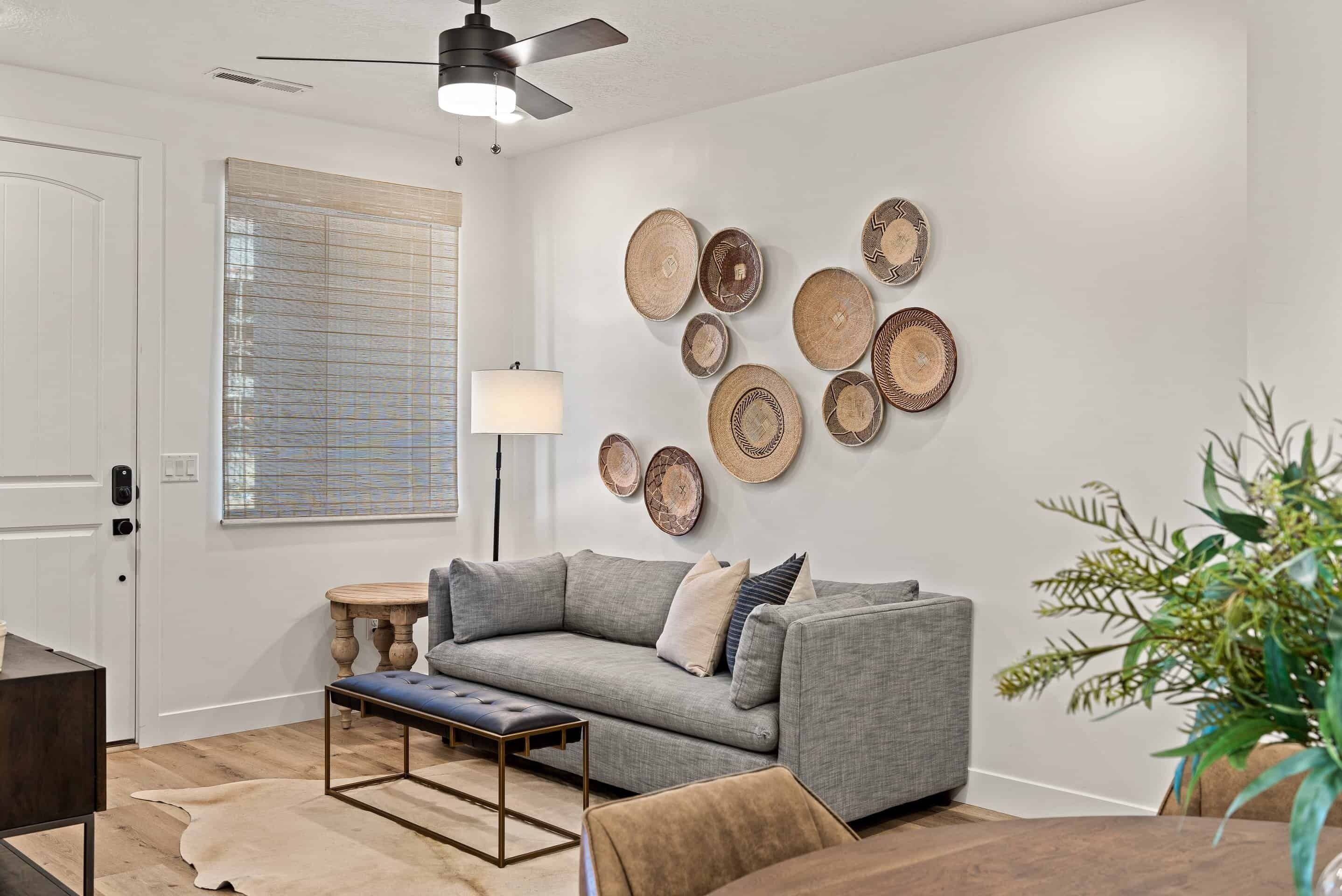 A living room with a grey sofa, a wooden coffee table, and a wall decorated with woven plates.