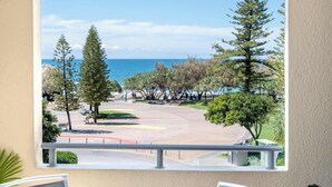 A balcony with a view of a coastal area, including trees and a road. - Tides & Tranquility - 2Bedroom Kings Beach Unit (Kings Beach)
