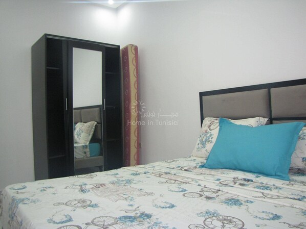 A bedroom with a bed, a wardrobe, and a mirror. - Nice apartment in chott mariem (Sousse)