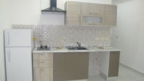 Una cocina compacta con un refrigerador blanco, una estufa y armarios de madera.