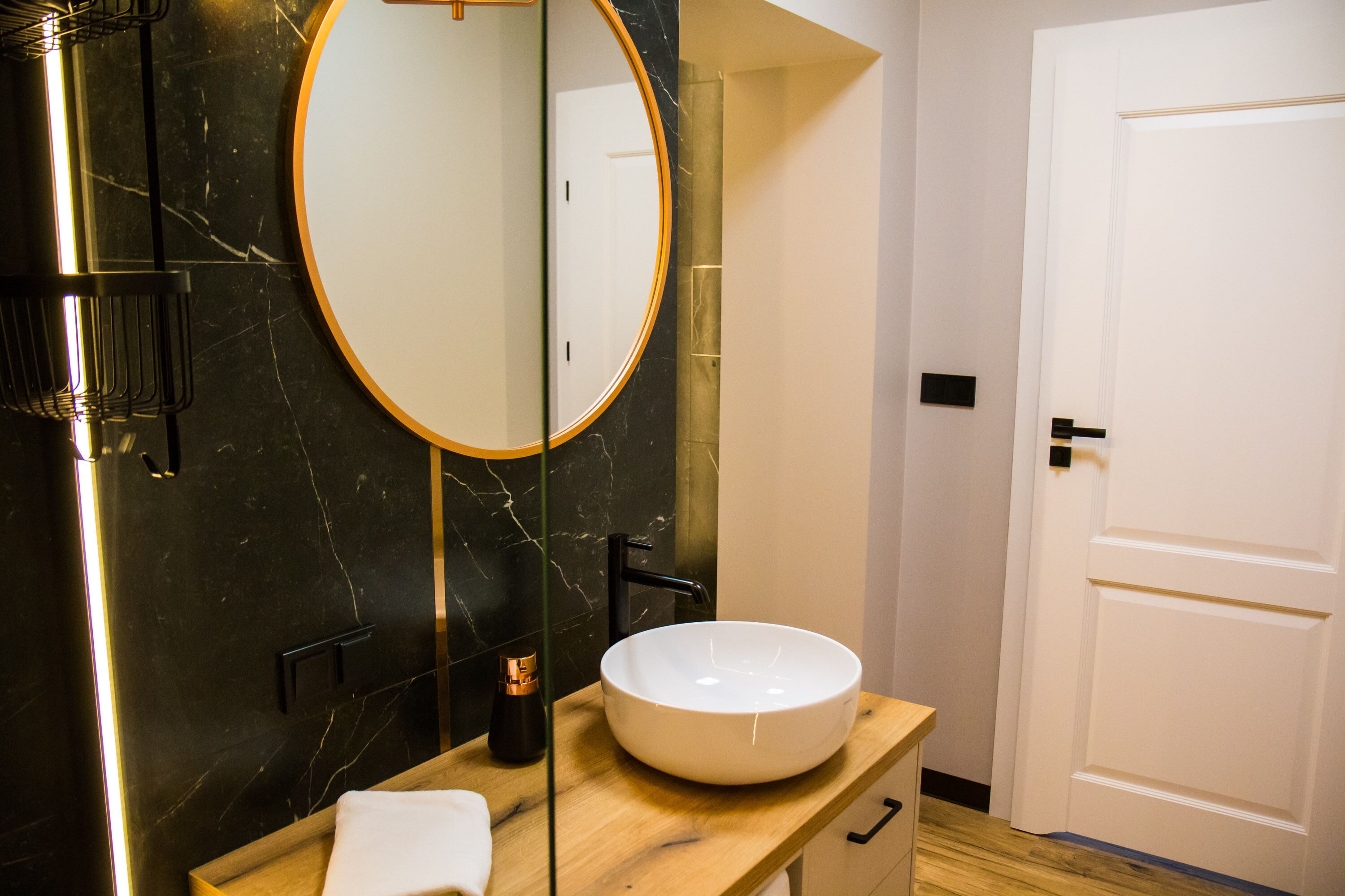 Ein modernes Badezimmer mit einem großen, ovalen Waschbecken, einem runden Spiegel und einer Holzkommode.