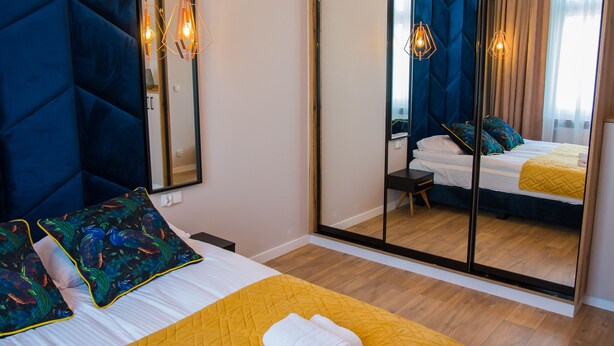 A hotel room with a large bed, a mirror, and a wooden floor. - Miedziany (Torun)