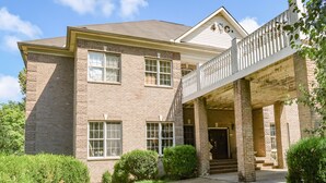 A two-story brick house with a balcony and a covered porch.