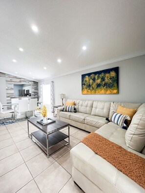 A modern living room with a sofa, coffee table, and a painting on the wall.