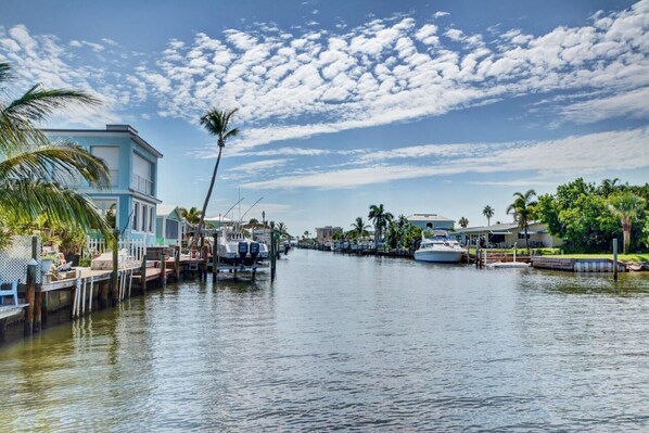 A marina with boats docked, a waterway, and buildings with balconies.